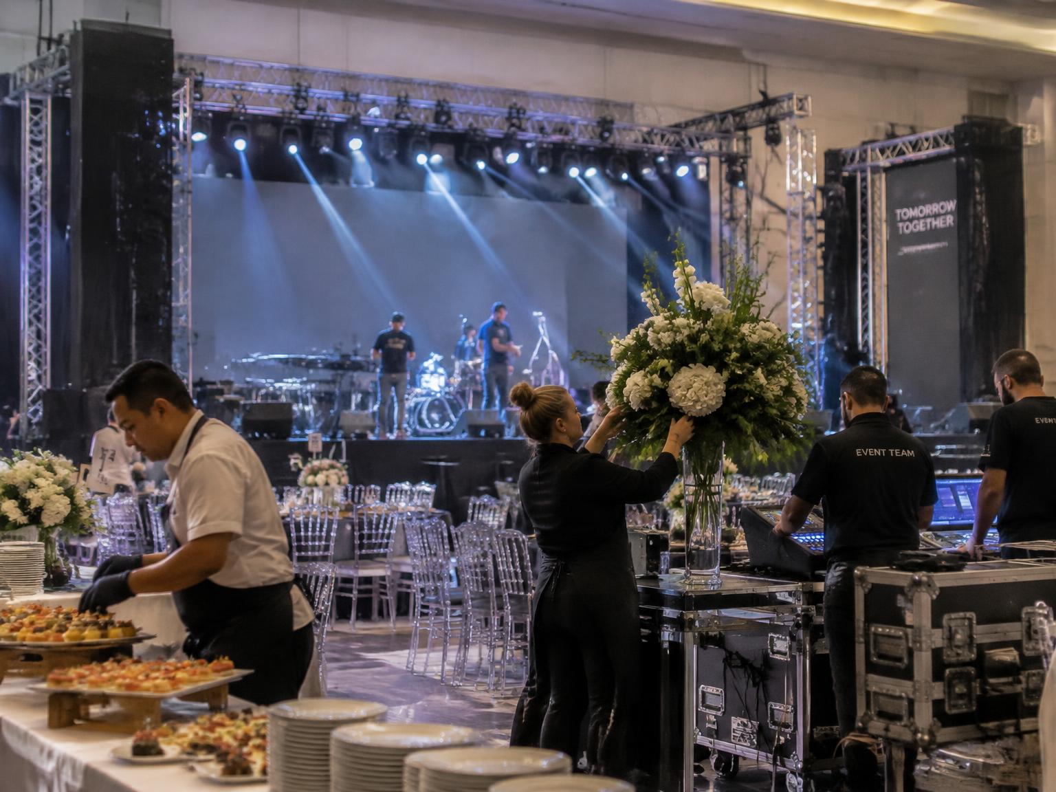 Traiteur, fleuriste et techniciens son et lumière préparant un gala